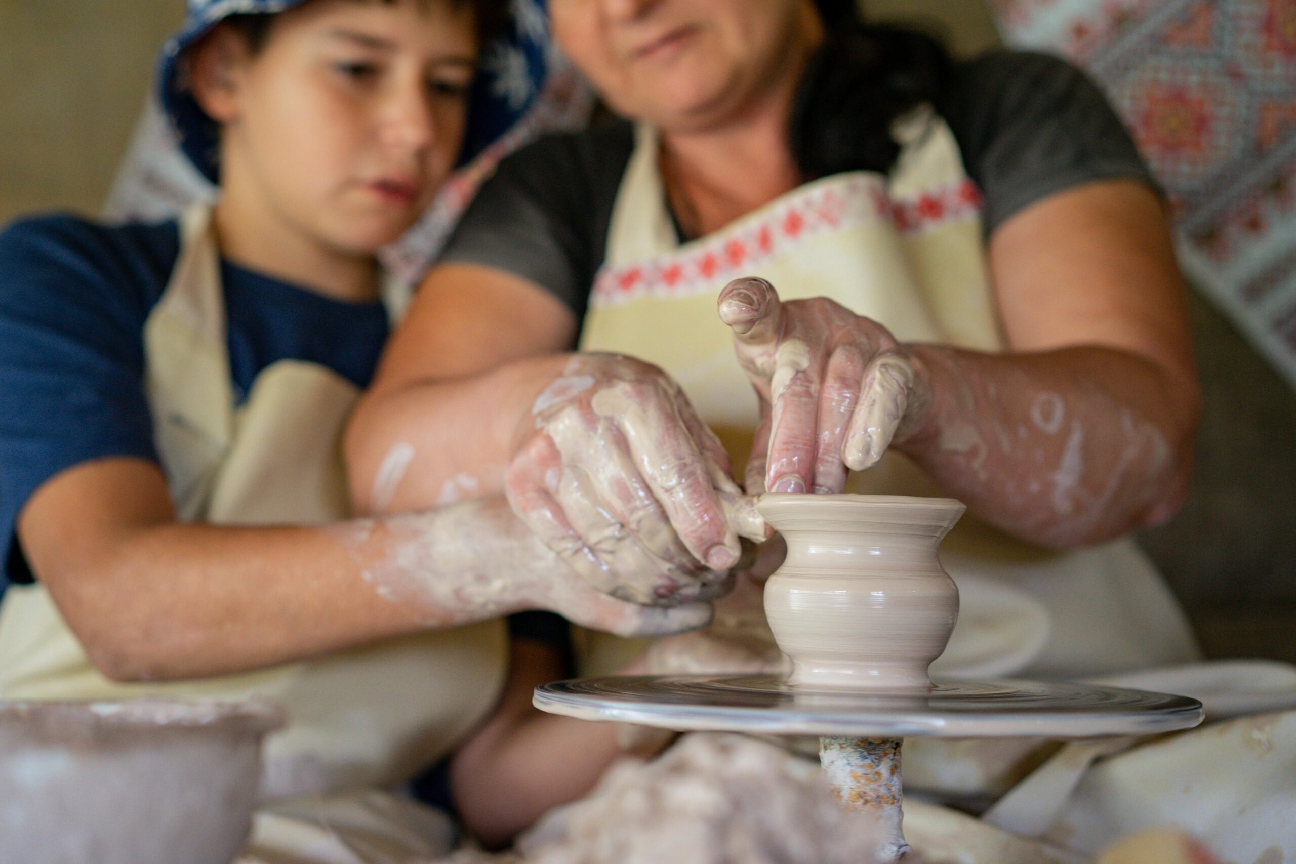 A group of tourists laughing as they shape clay pots under the guidance of an instructor