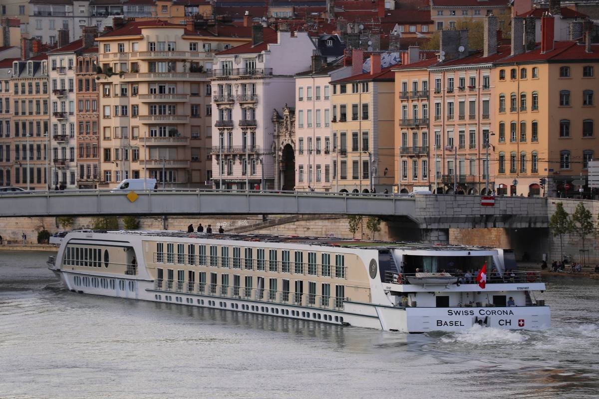 A scenic view of a river cruise ship navigating through calm waters under a blue sky.