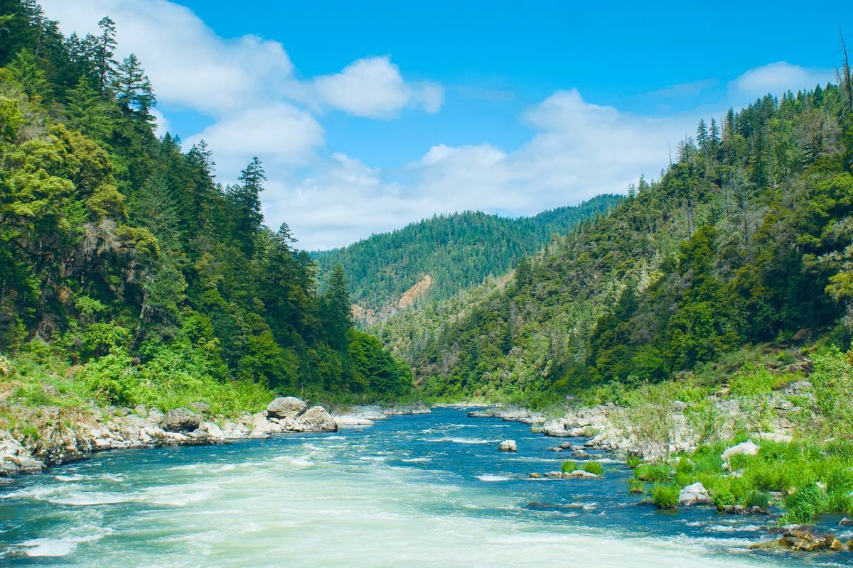 A river flows through lush mountains and forests.